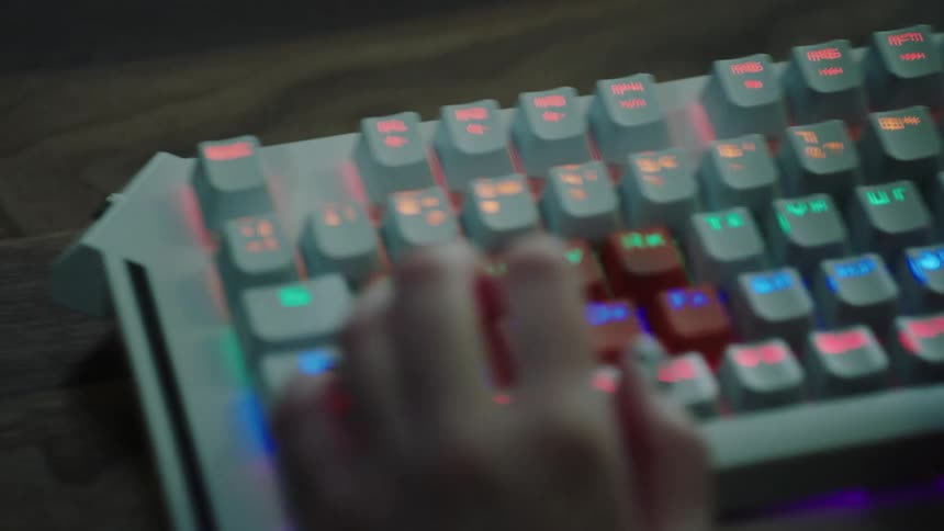 A womans hand typing on a keyboard on a desk