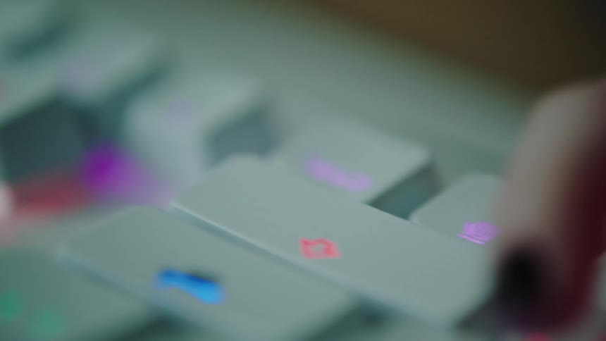 Woman with manicured nails typing on an rgb backlight white keyboard