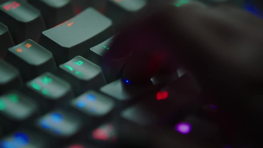 Hand hovers over brightly labeled keys typing on keyboard