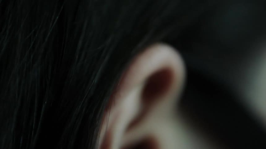 Woman hooks her black hair behind her ear