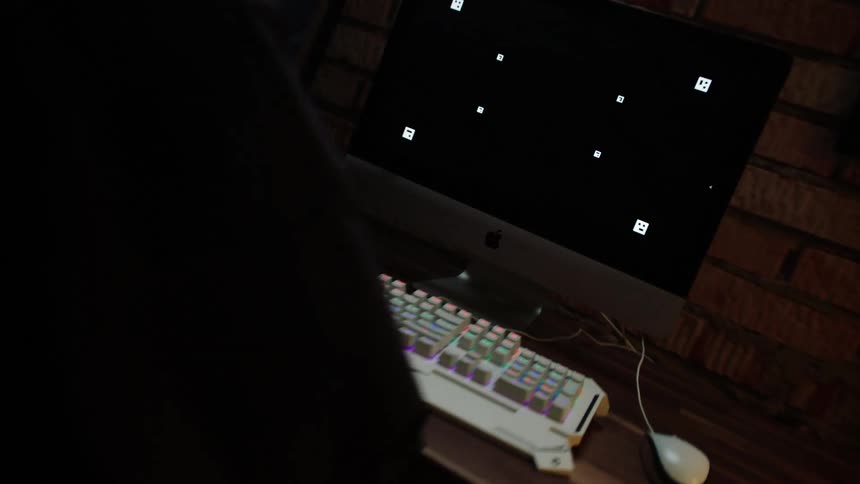 A person walks to a computer desk and sits to start typing on the keyboard