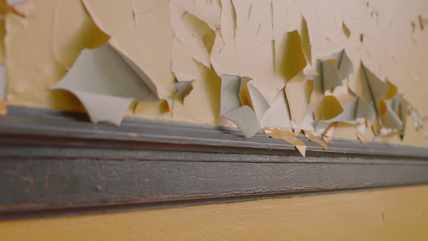 Peeling wallpaper on a wall above a ledge
