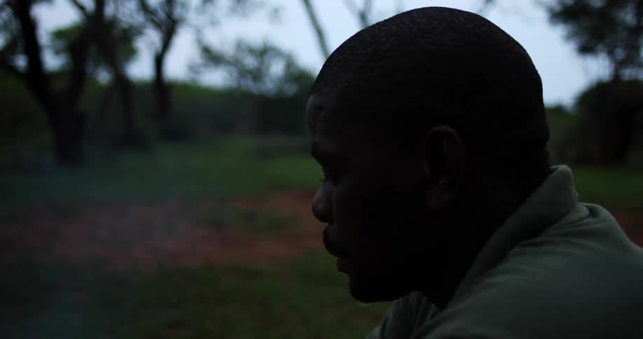 A man sitting outdoors lost in thought as thin smoke breezes by him