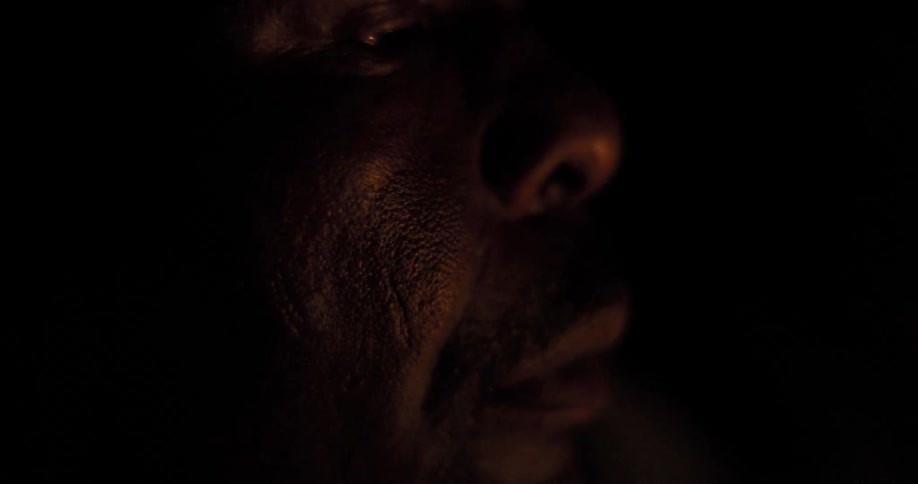 A mans face in the dark would light from a flame flickering