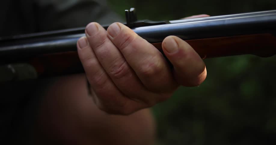 Hand holding a shotgun outdoors