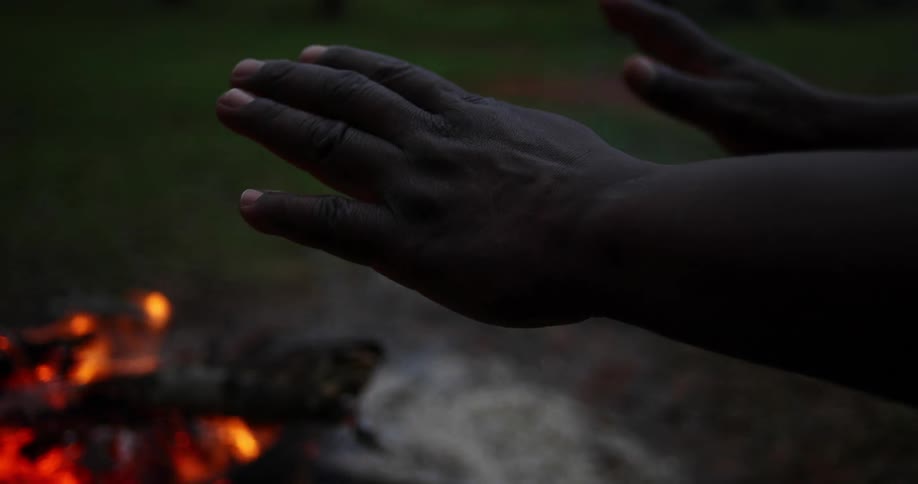 Close up of hands warming up in front of a campfire
