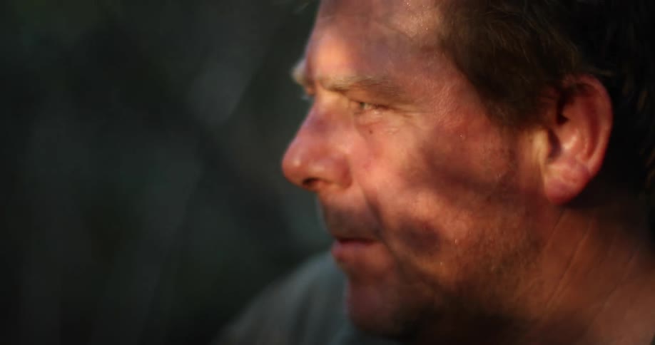 A man exhales while smoking and looking around outside