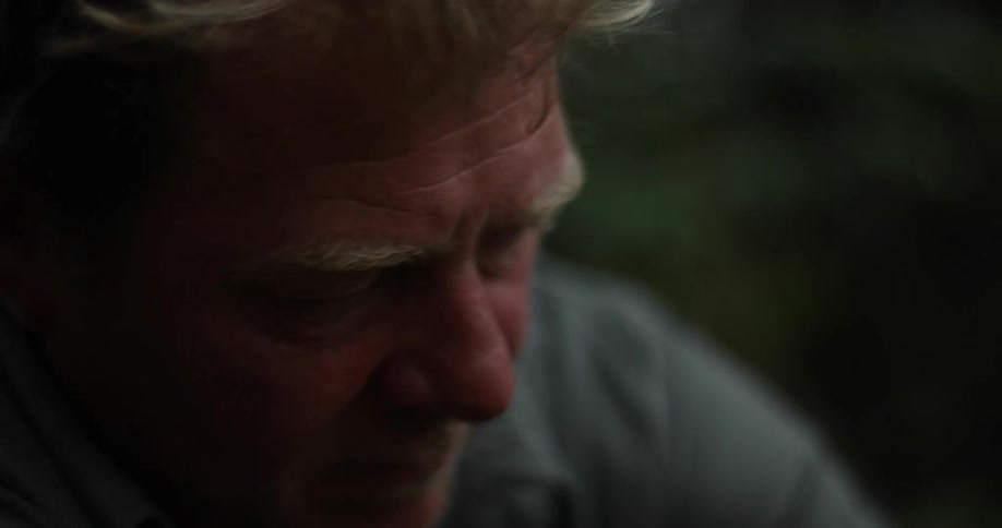 An older white man outdoors focusing on an activity
