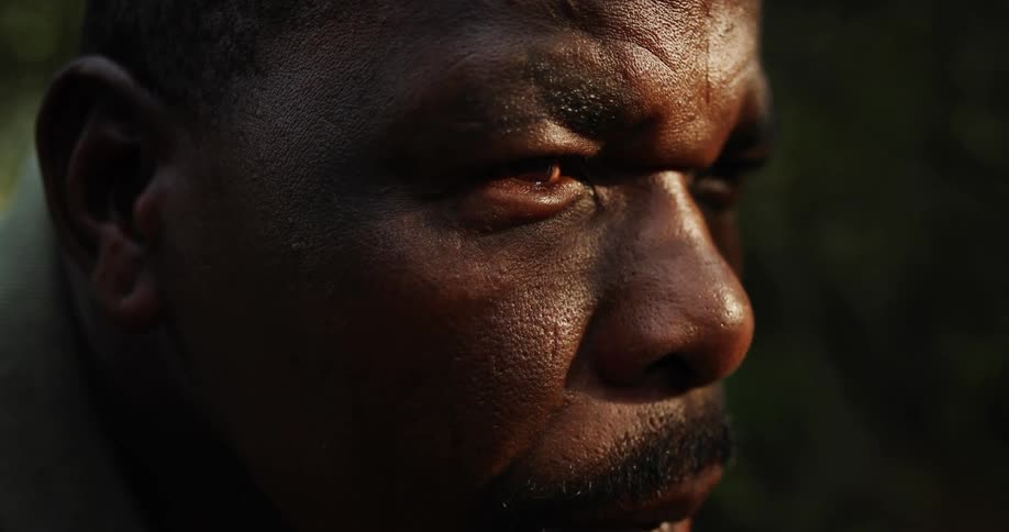 Black man squints his eyes as the sun shines into them