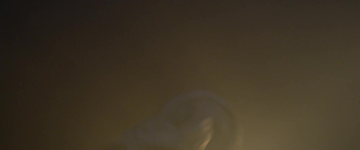Hooded man wearing armor runs in a room with flashing yellow lights