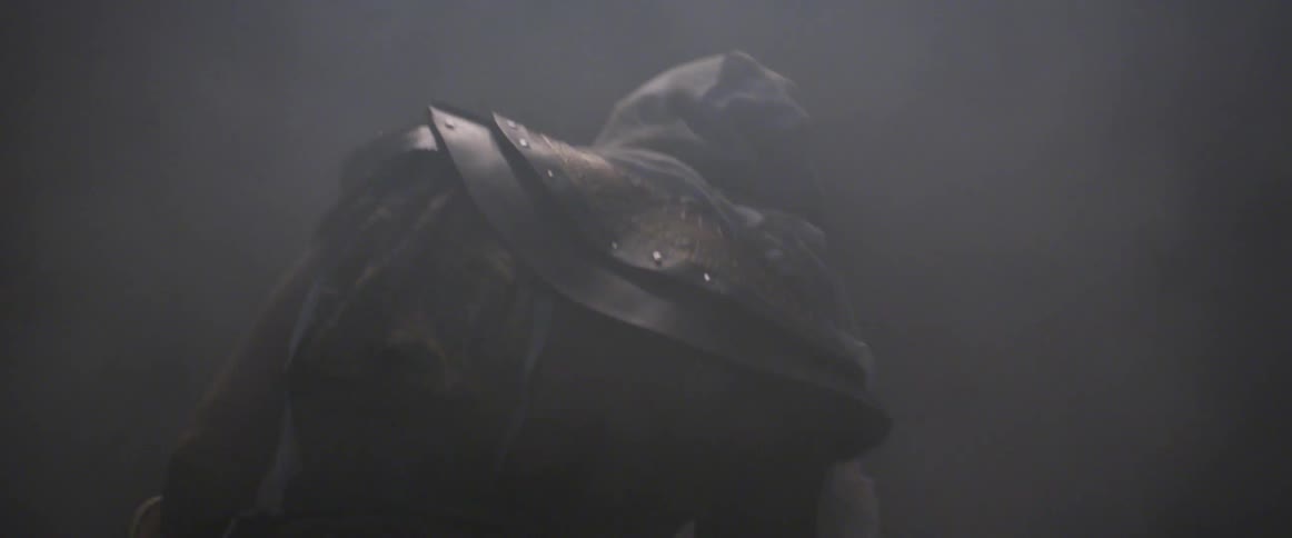 A person in a costume walks through the fog and towards a light