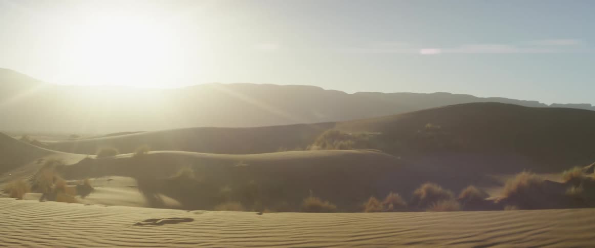 A man runs and jumps off the sand dune
