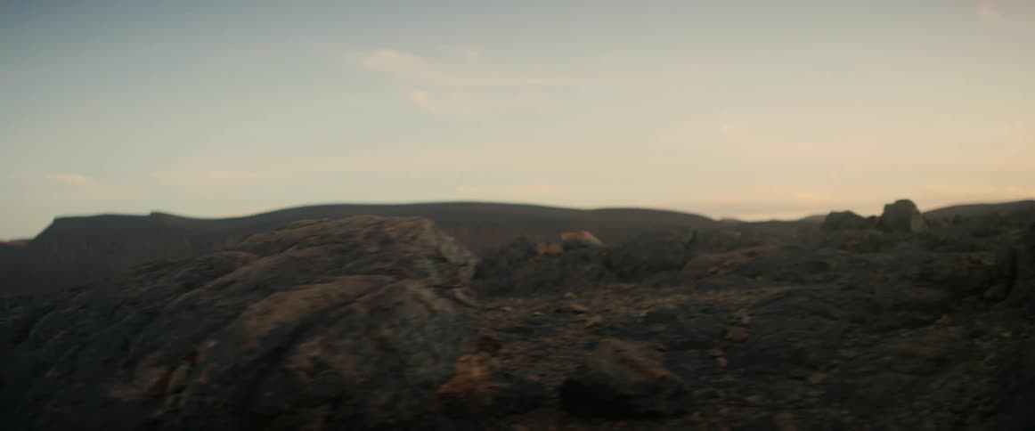 A person jumps from one rock to another in rugged terrain