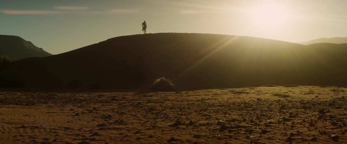Man standing on top of a hill at sunset