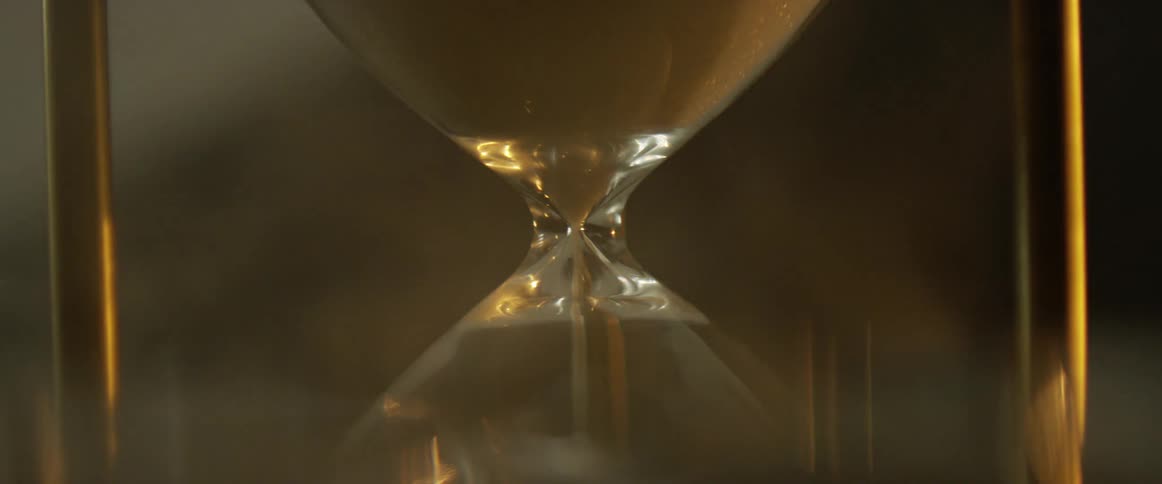 Sand flows through an hourglass and mist floats around it