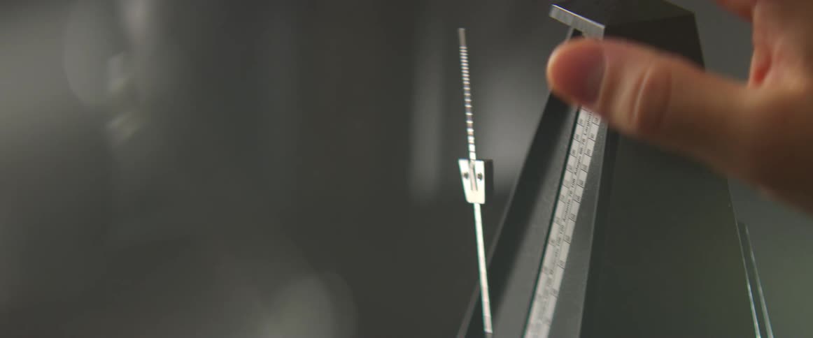 Hand puts the pendulum of a metronome in motion