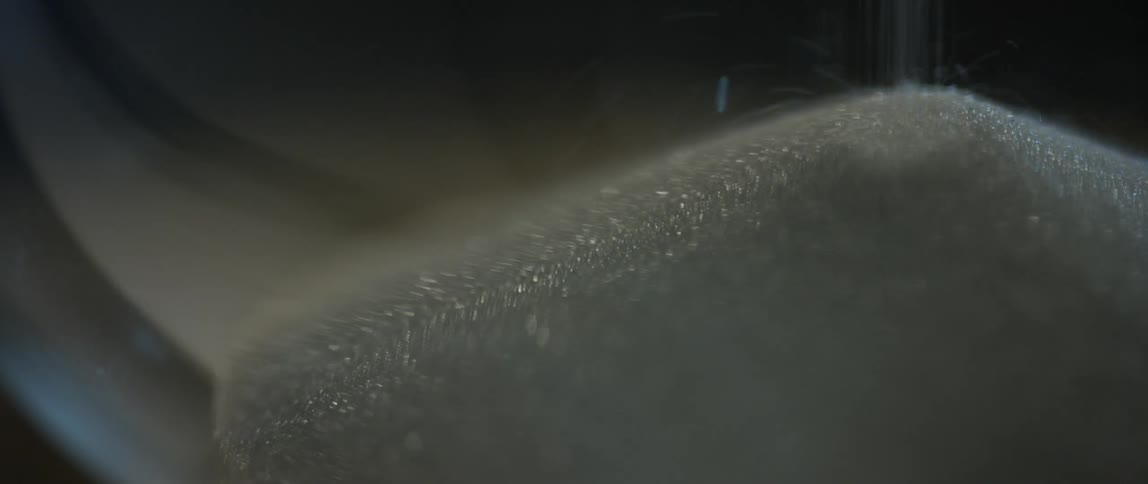Grains of sugar fall forming a pile