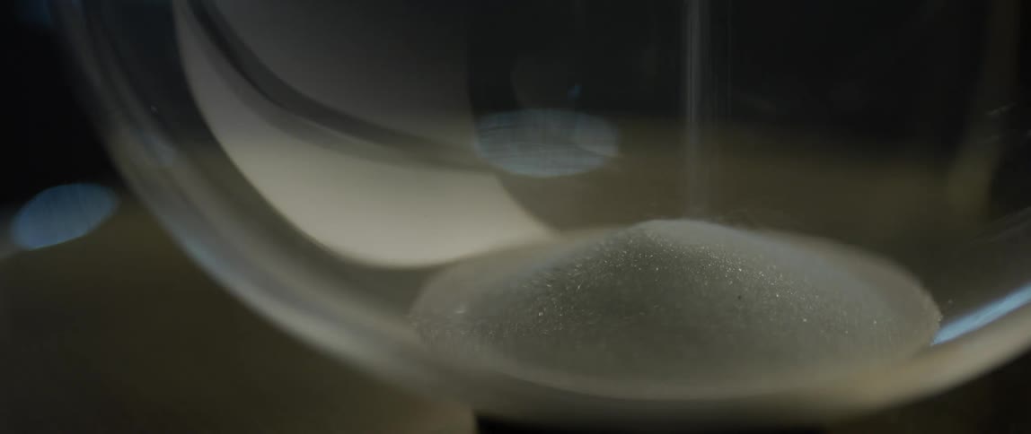 Stream of salt being poured on a mound of salt in a glass jar