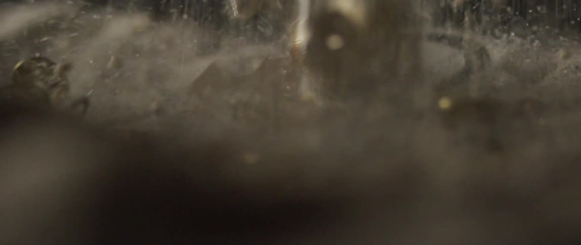 Clock pieces fall on the ground in a cascade of dust and dirt