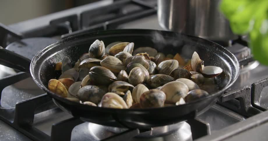 Oyster cooking in oil on a frying pan over the burner of a kitchen