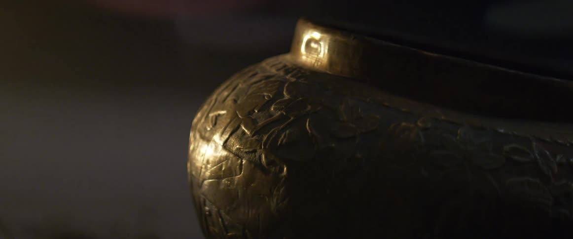 Carved metal vase on the floor under moving lights