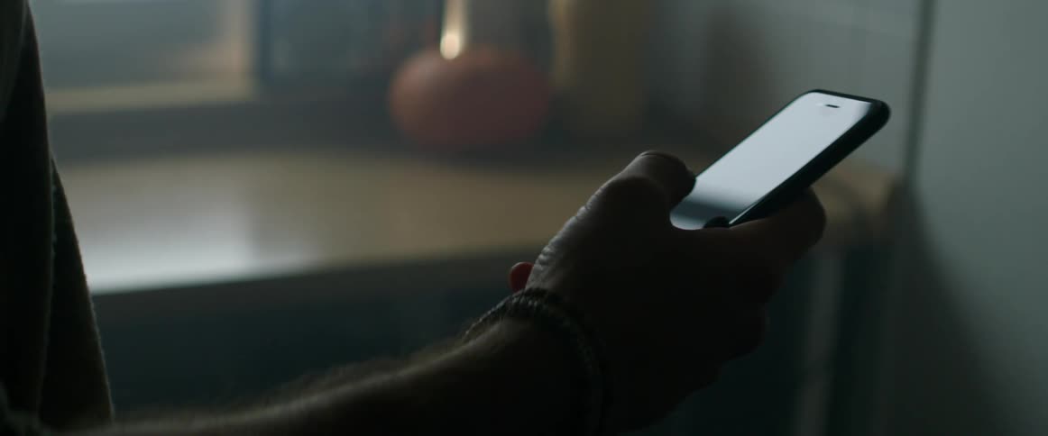Man with bead bracelets uses a smartphone