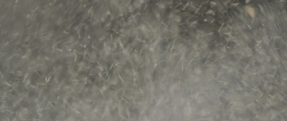 Hoses spray water upward in a circle and create ice as the water hits the air