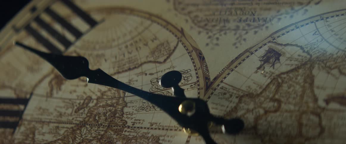 Hand of a clock shows the time on a clock decorated with maps