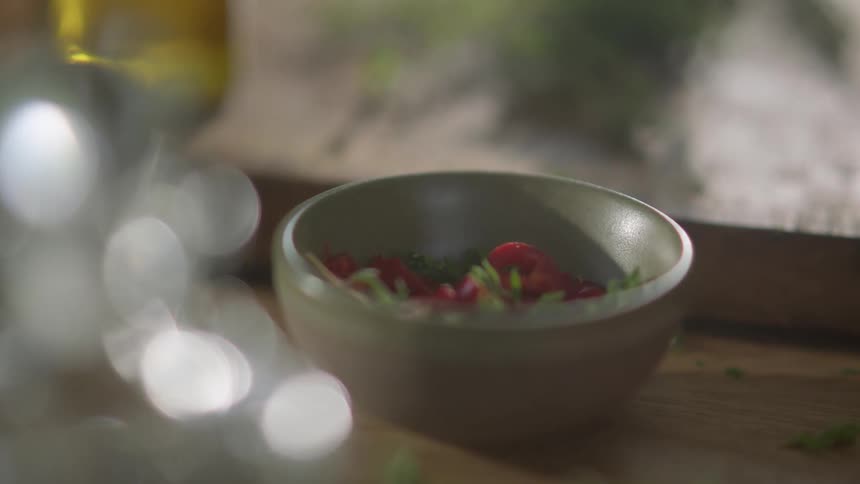 Fresh green herbs are dropped into a bowl full of red berries