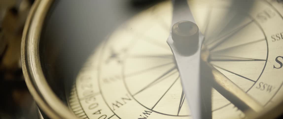 Close up of a compass dial with the needle moving over the compass rose