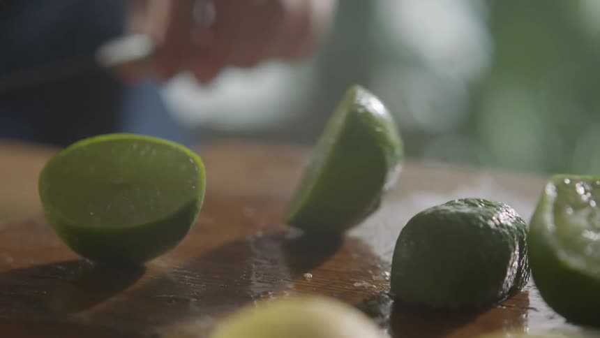 A white male cuts a lime in half with a knife in a kitchen