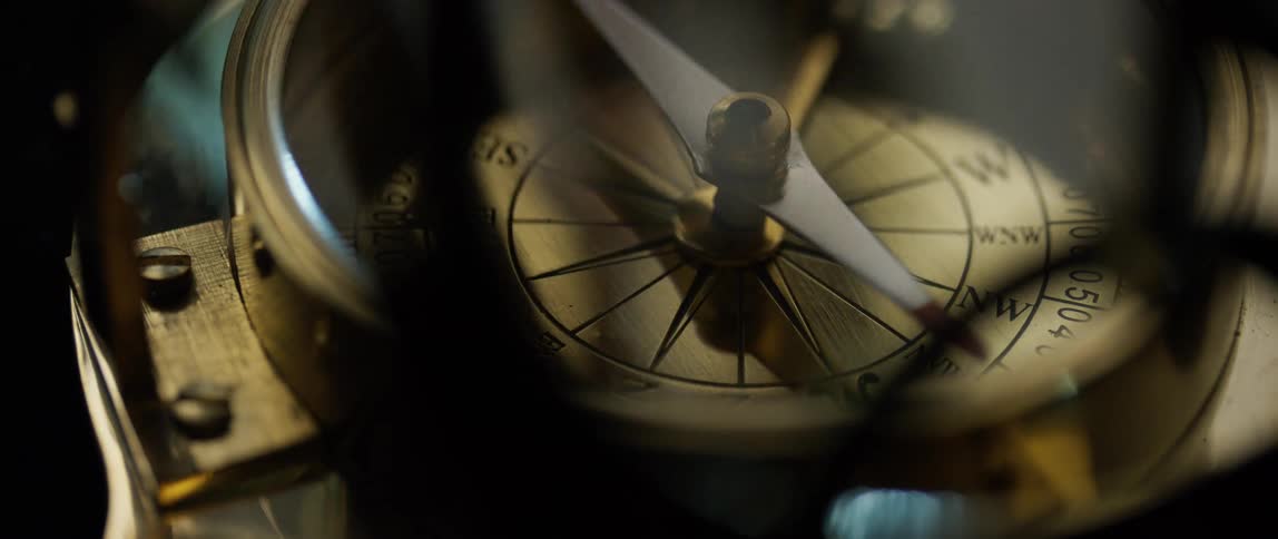 Close up of a compass needle moving around the dial