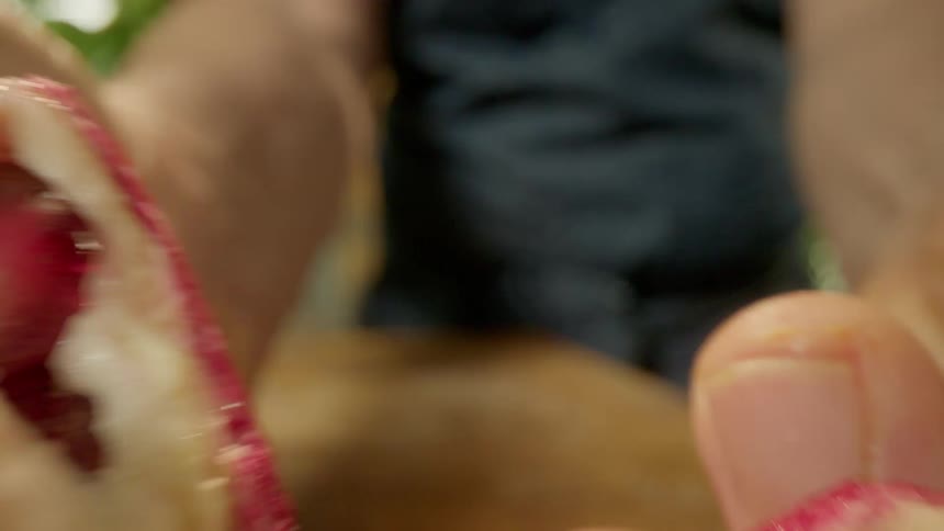 A cook opens a pomegranate