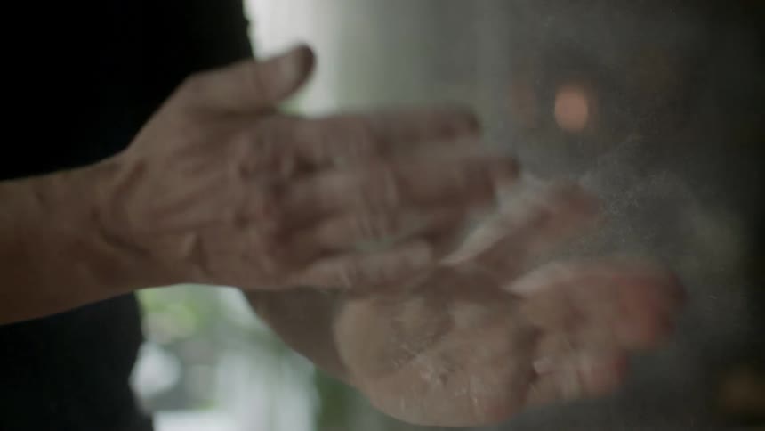 A person claps and brushes their hands together in order to remove all the white dust covering them