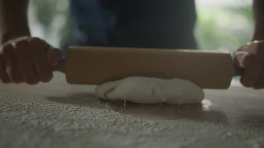 A man rolling out dough