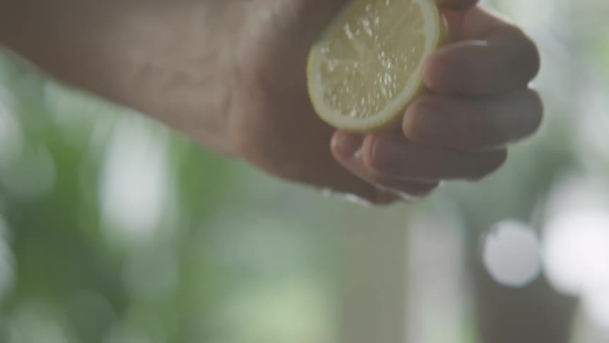 Man squeezes a lemon or lime with his own hand in a kitchen