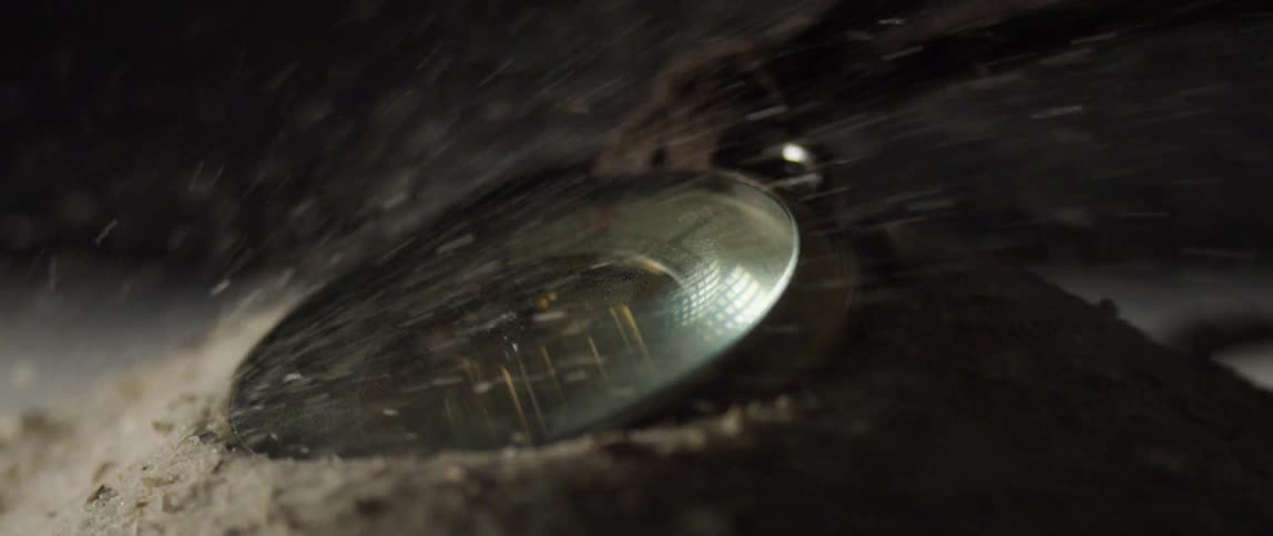 Sawdust flows over face of metal disk hung on strap