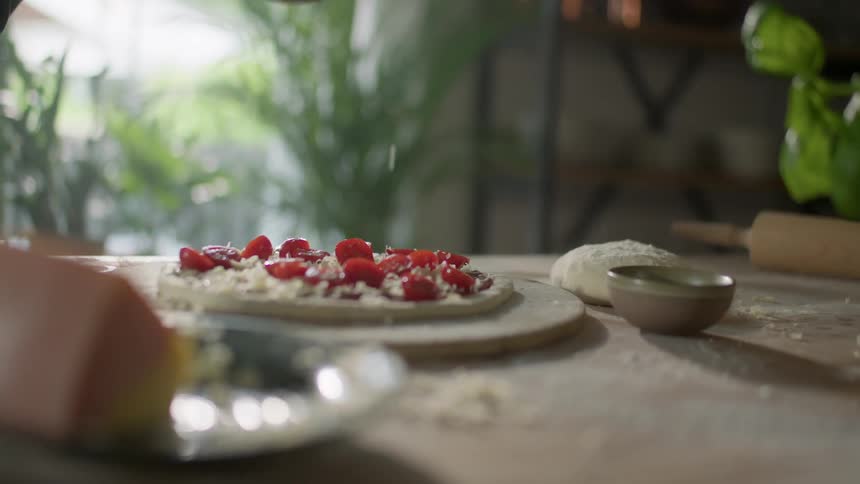 A person sprinkles fresh cheese on a homemade pizza
