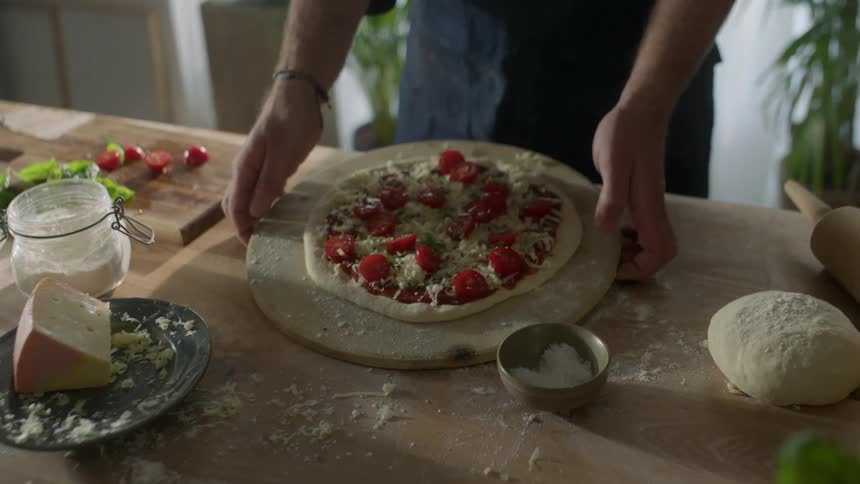 A man brings a pizza over to the oven