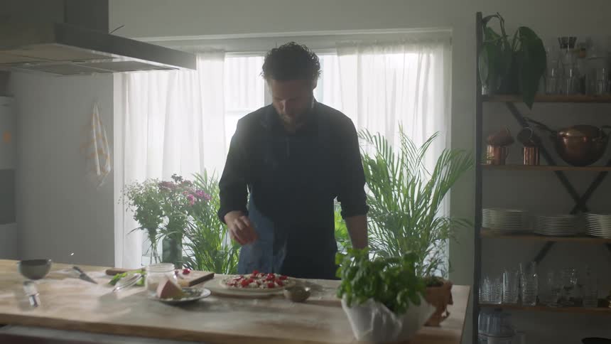 Bearded man makes homemade pizza on the kitchen of his house