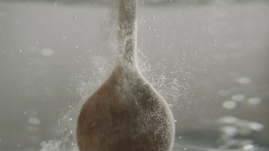 Wooden utensil propped into bubbling clear liquid creating fizzy effect