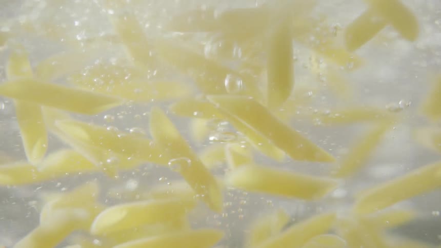 Short pasta rigati falling into boiling water