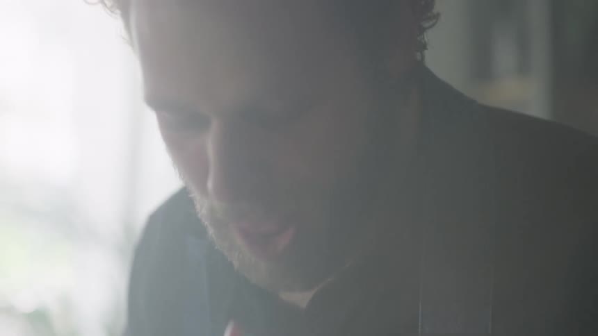 A man tastes food as he prepares it at home