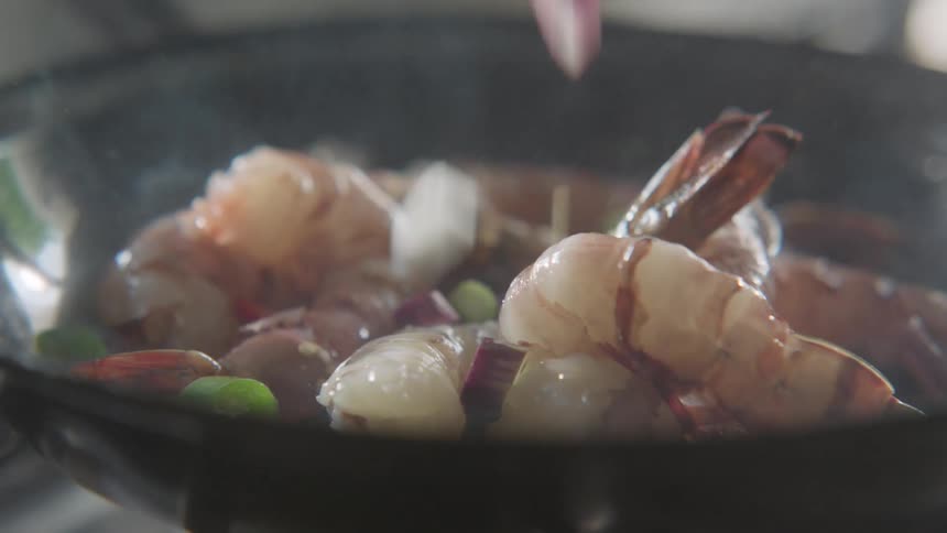 Shrimp and vegetables being fried in a black skillet