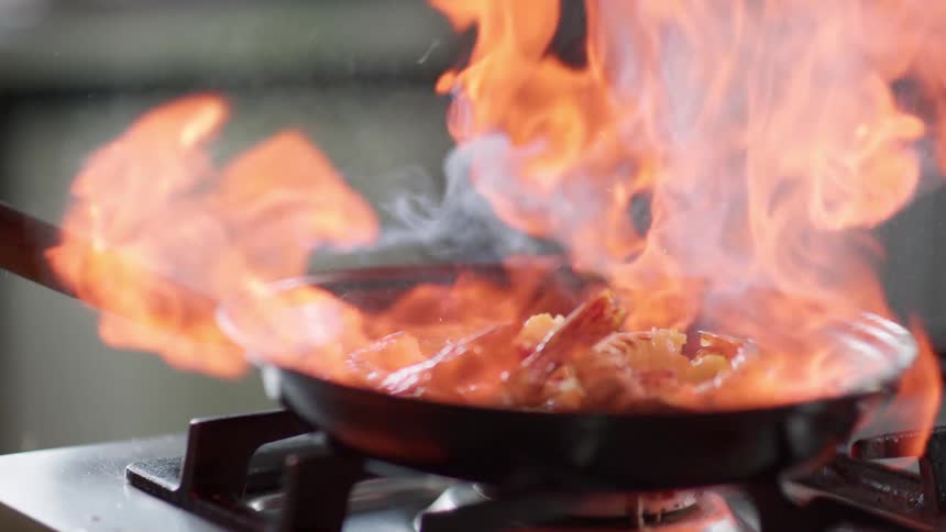 Water is poured on a hot skillet with vegetables and shrimp
