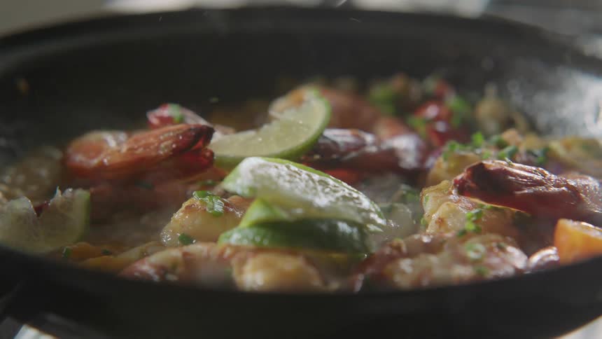 Slices of limes dropping on a shrimp meal while sauteing