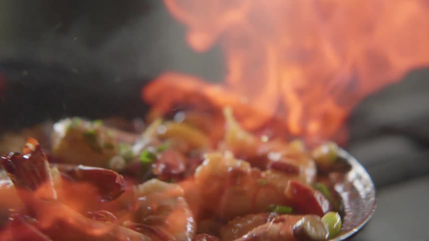 Seafood cooking in a frying pan flames up when wine is added