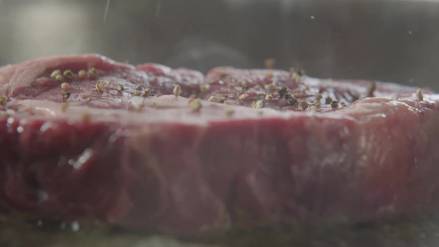 Spices are dropped on the steak