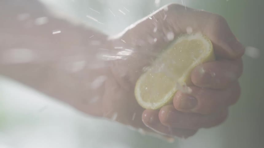 A mans hand squeezes a lemon in the kitchen