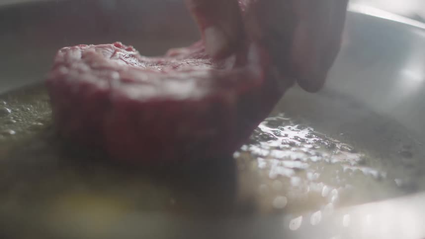 Steak sizzling in frying pan